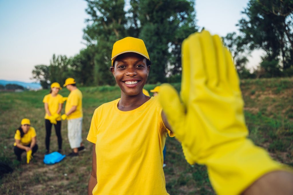 Cute female volunteer cleaning garbage in nature with her friends.